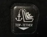 Symbol mocowania fotelika ISOFIX z kotwicą i dzieckiem. Oznaczenie TOP-TETHER dla bezpieczeństwa najmłodszych.