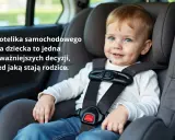 Uśmiechnięty chłopiec w foteliku samochodowym Titan Pro i-Size. Bezpieczeństwo dziecka w podróży to priorytet.