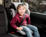 Chłopiec w foteliku samochodowym Britax Römer, zgodnym z normą ece r44/04, wyciąga język.
