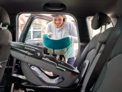 Kobieta wkłada do samochodu fotelik Maxi-Cosi Coral 360 z bazą.