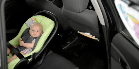 Niemowlę w foteliku na tylnym siedzeniu samochodu. Brak fotelika grozi mandatem.