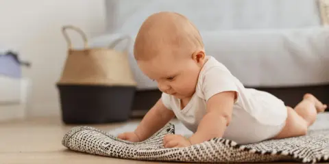 Dziecko na brzuchu, ćwiczy **wysoki podpór kiedy** na dywaniku.