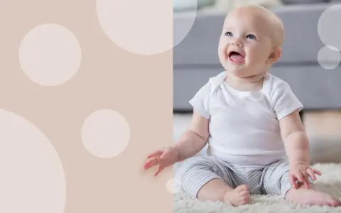 Uśmiechnięte dziecko siedzi na dywanie. Czy 5 miesięczne dziecko można sadzać na kolanach?