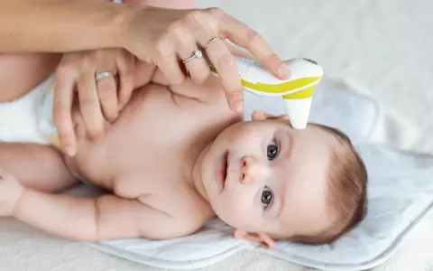 Mama mierzy temperaturę niemowlaka termometrem bezdotykowym.