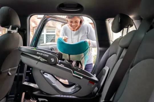 Kobieta wkłada do samochodu fotelik Maxi-Cosi Coral 360 z bazą.