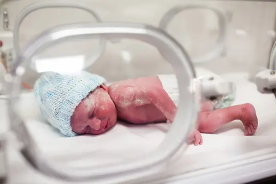 Maleńki noworodek w niebieskiej czapce leży w inkubatorze. To dziecko urodzone w 20 tygodniu ciąży, potrzebujące szczególnej opieki.