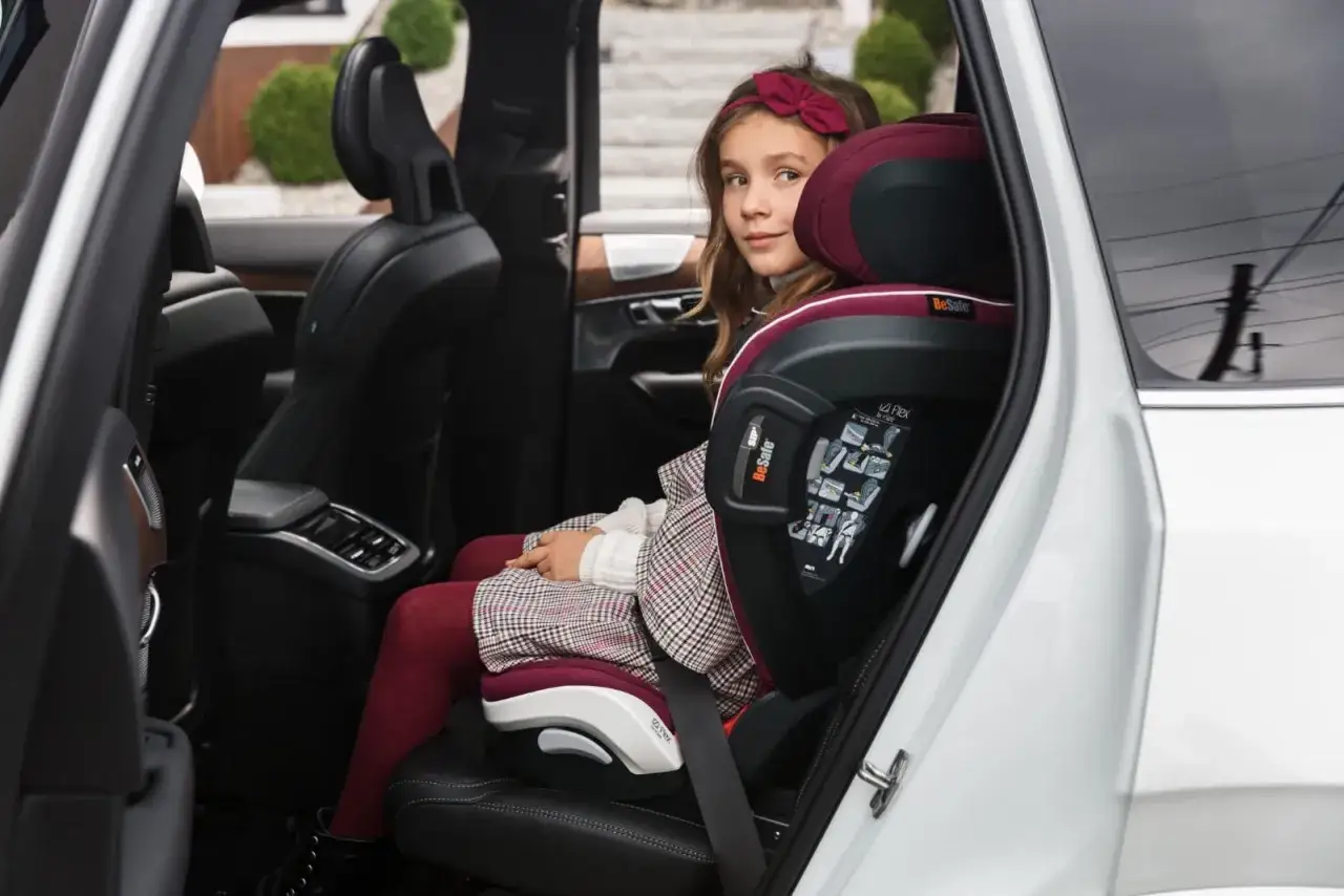 Dziewczynka w stylowym ubraniu siedzi w foteliku samochodowym BeSafe iZi Flex Fix, który jest przeznaczony dla dzieci o wadze 15-36 kg.