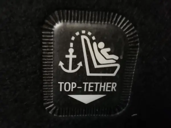 Symbol mocowania fotelika ISOFIX z kotwicą i dzieckiem. Oznaczenie TOP-TETHER dla bezpieczeństwa najmłodszych.