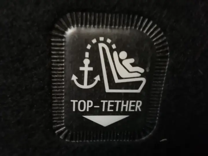 Symbol mocowania fotelika ISOFIX z kotwicą i dzieckiem. Oznaczenie TOP-TETHER dla bezpieczeństwa najmłodszych.